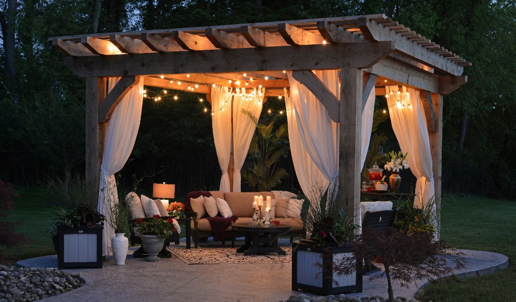 Outdoor living space with fairy lights and billowing curtains under a pergola