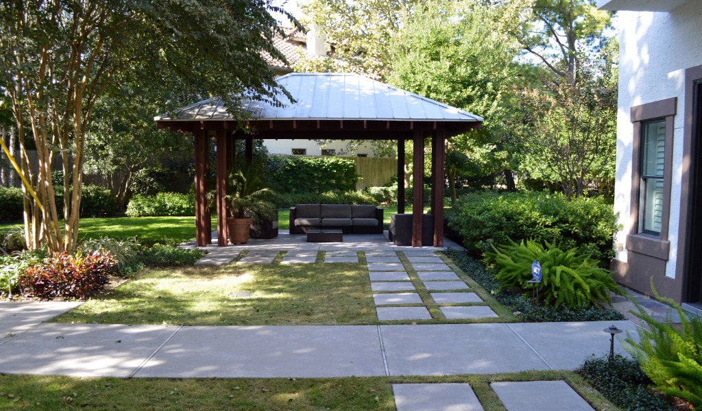Custom design-build outdoor living space with an outdoor kitchen, shade structure and walkway.