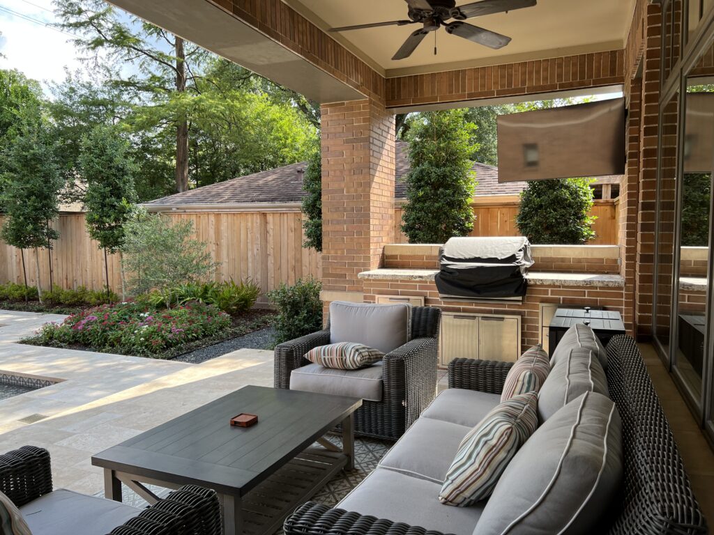 Outdoor kitchen area with whicker seating and built in grill.